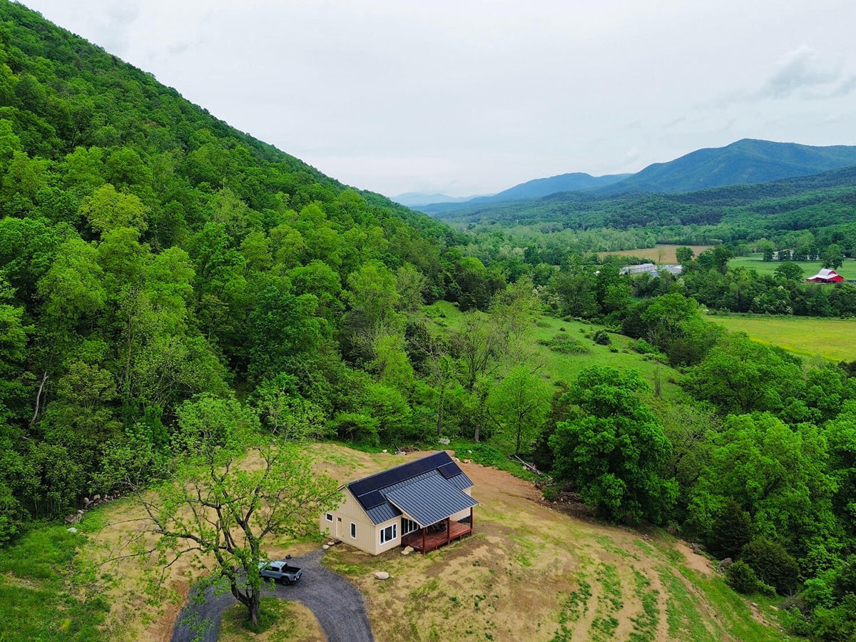 Aerial view of a modern cabin nestled in lush green hills in West Virginia, Design with Frank.