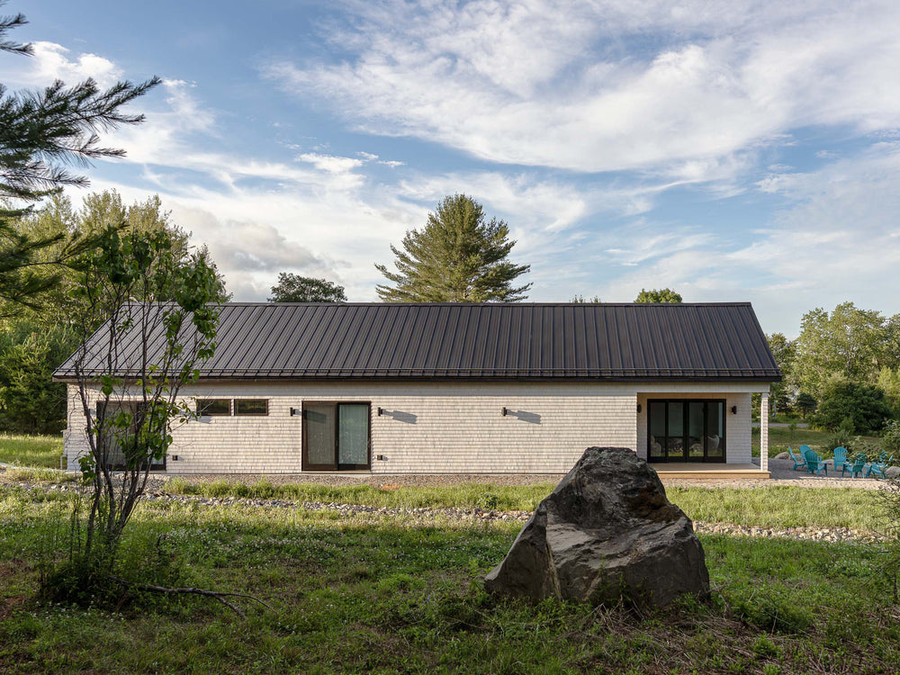 Cedar shingle modern farmhouse with black metal roof in Monroe, Maine