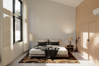 Primary bedroom in the 2 bedroom modern cabin house plan — inclined ceiling, timber wardrobe and black-frame windows over a snowy forest