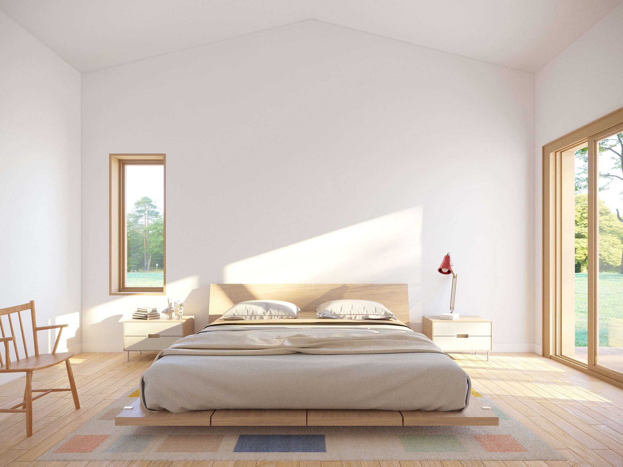 Minimalist master bedroom with vaulted white ceiling, low platform bed with oak headboard, light oak floor, narrow vertical window, and large wood-framed sliding door with garden view