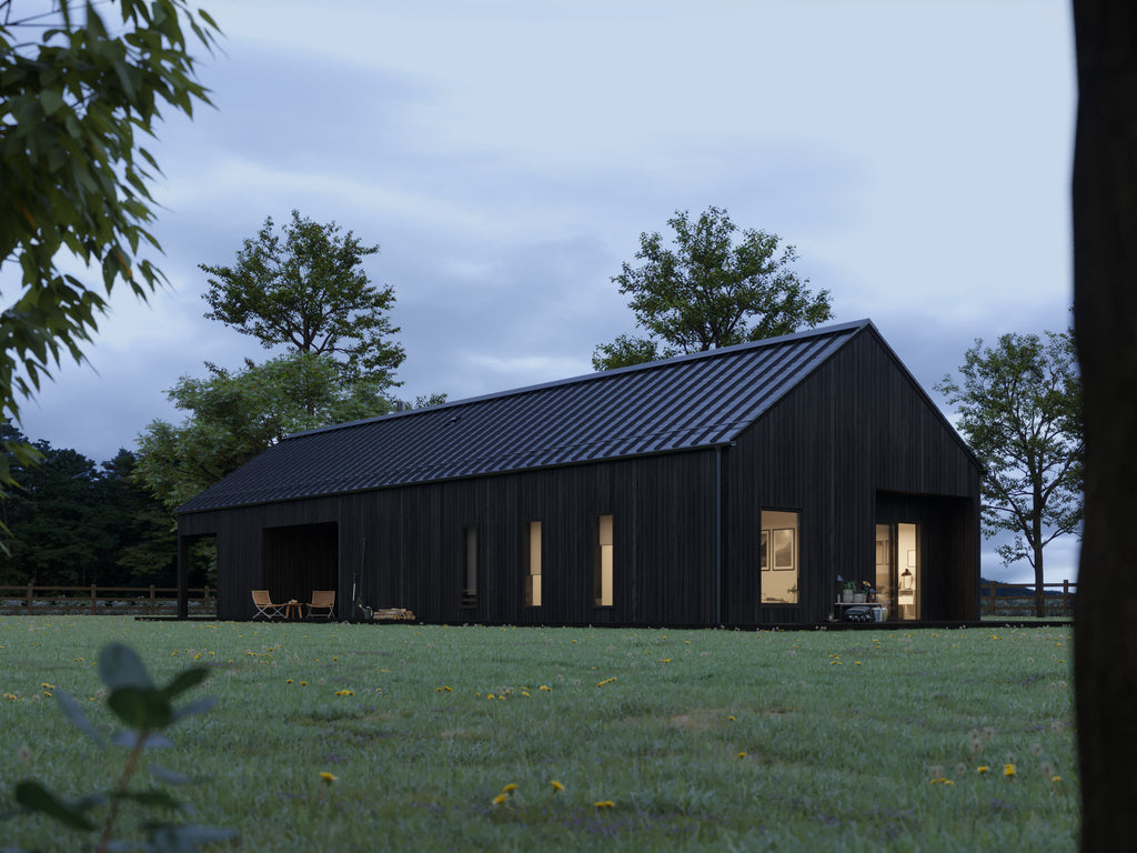 Black barn house with charred wood cladding and black standing seam metal roof at dusk, side elevation showing warm interior lighting through bedroom and living room windows
