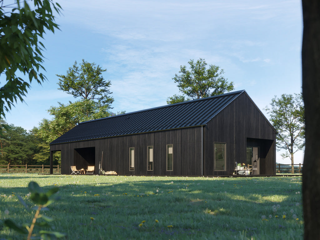 Contemporary black barn home with dark charred wood vertical siding and black pitched metal roof, daytime side elevation showing covered porch, tall windows, and outdoor seating in green meadow