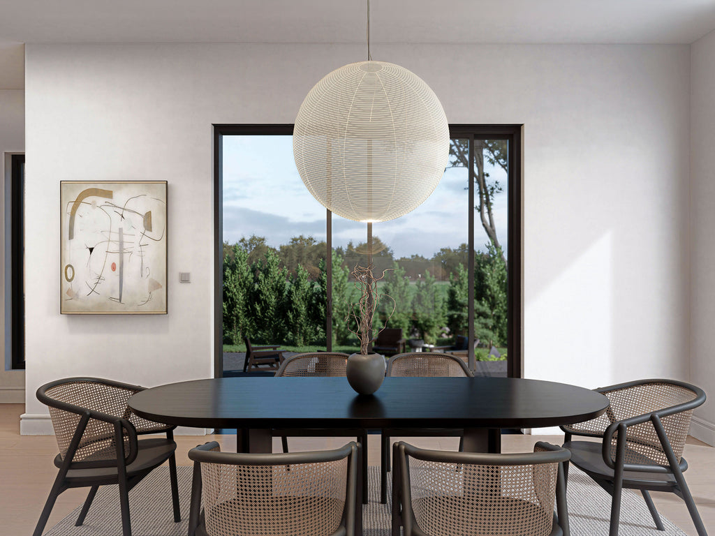 Modern barn house dining room with black oval table, cane chairs, globe pendant light and large black-frame window overlooking backyard