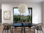Modern barn house plan dining room — black oval table, cane chairs and black-frame window with lake view