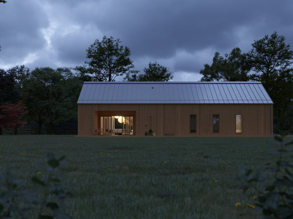 Modern barn house with natural vertical wood cladding and low-pitch silver standing seam metal roof at dusk, warm interior lights glowing through open living area and narrow flanking windows in a meadow setting