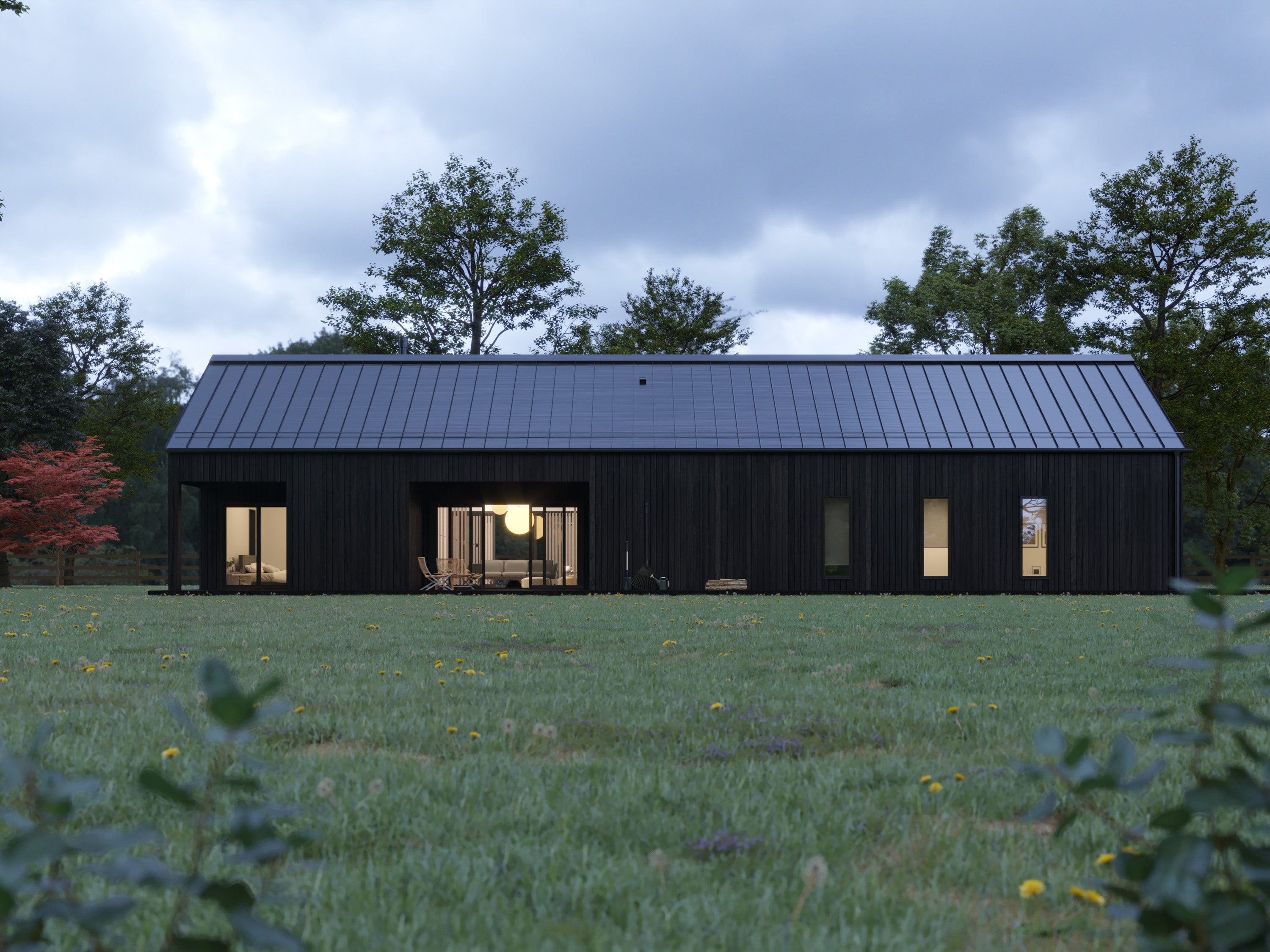 Modern black barn house with charred wood vertical cladding and black standing seam metal roof at dusk, warm interior lights glowing through open living area and flanking windows