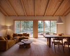 Open-concept living and dining room in Japandi minimalist house plan with wood accents and large windows
