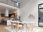 Nordic barndominium dining room with loft overhang, white oval table, kitchen island and black-frame floor-to-ceiling windows