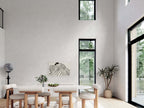 Nordic barndominium floor plan dining room with double-height black-frame windows, vaulted ceiling, white oval table and natural wood flooring