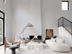Nordic barndominium living room with double-height vaulted ceiling, statement fireplace, curved sectional sofa, black-frame windows and black iron staircase
