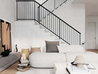 Nordic barndominium living room with double-height vaulted ceiling, black iron staircase and railing, neutral sectional sofa and loft overlook
